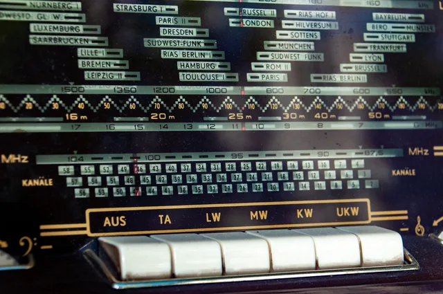 Close-up of a vintage radio dial displaying frequency bands and station names. Audio-Frequenz und Reichweite