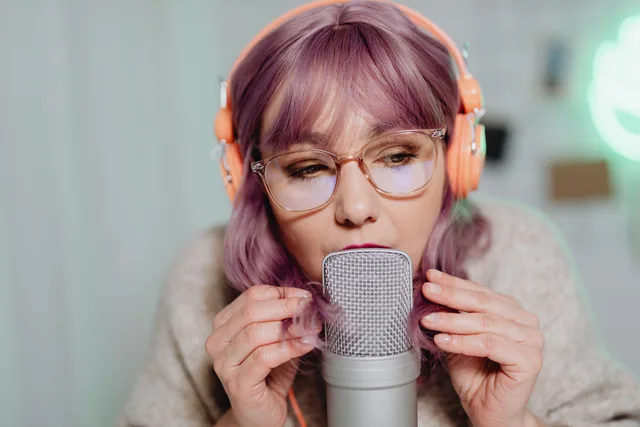 Close-up of a woman podcaster speaking into a microphone in a studio setting. Ein Audioformat zum Kommunikationsziel auswählen