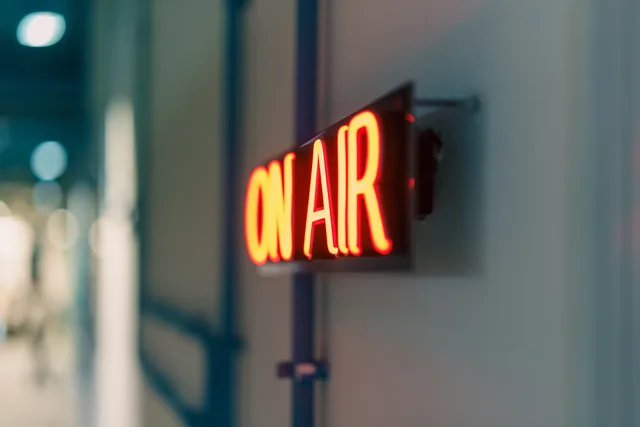Bright red 'On Air' neon sign captured indoors, ideal for media content. Kontextbezogene Audiozielgruppen auswählen